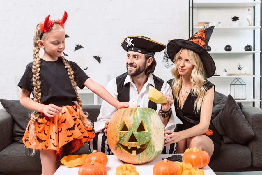 A family in Halloween costumes carving pumpkins
