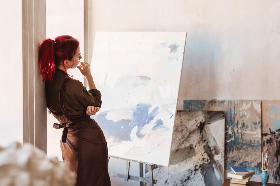 A creative artist in front of her painting